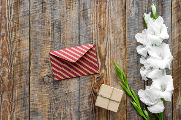 Congratulation. Envelope and box in kraft paper near flower gladiolus on wooden table top view copyspace