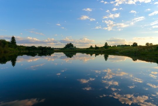 Pond with reflection of the setting sun with clouds