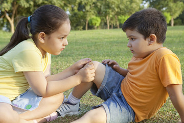 Girl putting band-aid on brothers leg