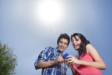 Cheerful young couple looking at mobile phone 