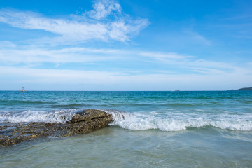 wave of green ocean on sandy beach and blue sky