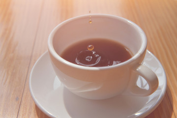 good time or morning Tea drop in a cup on the wooden table. soft focus