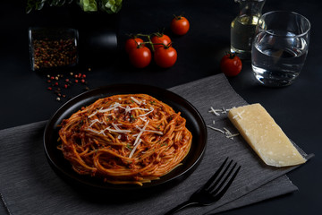 Spaghetti pasta with tomato sauce ,fresh tomato and cheese on dark background, selective focus