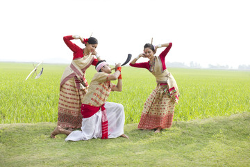 Bihu man playing on a pepa while Bihu women dance to his tune 