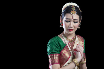 Sad Bharatanatyam dancer performing over black background