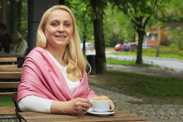 Smiling beautiful woman 45 years old drink coffee in a cafe.