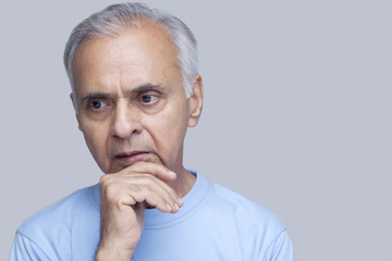 Close-up of senior man thinking over colored background 