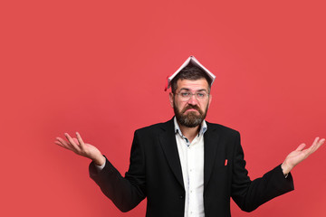Man in classic outfit with beard holds book on head