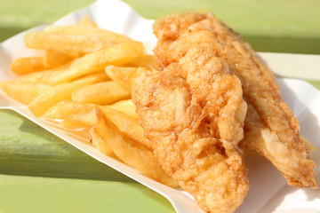 Tasty fried fish and chips on wooden bench