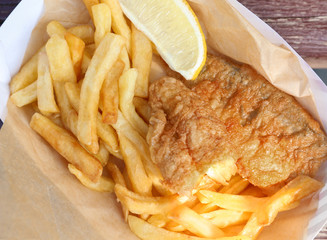Tasty fried fish and chips with lemon slice on wooden background