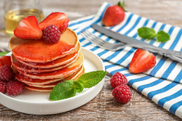 Plate with delicious pancakes on table