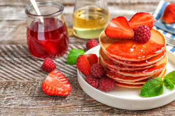 Plate with delicious pancakes on table