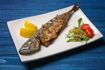 Grilled tasty fish on white plate with vegetables