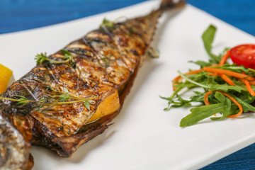 Grilled tasty fish on white plate with vegetables
