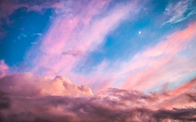 Moon in a pastel-clouded blue sky.