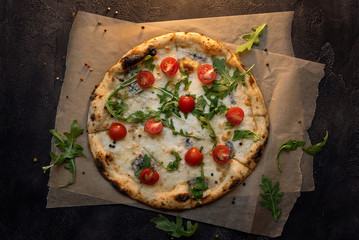 cheese pizza with paper and tomato on dark concrete background top view