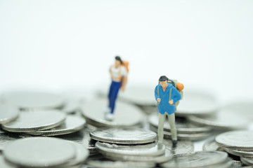 Travel, saving, planing concept. Close up of two miniature mini figures with backpack walking on pile of coins
