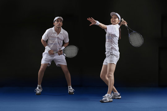Male and female players playing tennis doubles at court