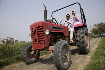 Low angle view of an Indian couple sitting in a tractor 