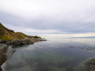 Clear ocean water in hidden isolated bay with a rock beach 