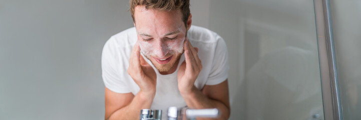Man washing face banner panorama. Person cleansing with facial cleanser face wash soap in bathroom...