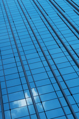 Fototapeta na wymiar Glass facade of a building with a reflection of the sky with a cloud