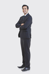 Obraz na płótnie Canvas Full length portrait of young businessman in suit isolated over gray background 