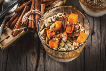 Traditional autumn dishes, spicy pumpkin pie overnight oatmeal with cinnamon, anise and maple syrup. In portioned glasses, on wooden old rustic table. Copy space
