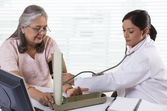 Female doctor checking patient's blood pressure 