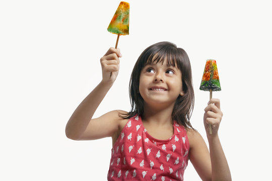 Little girl holding two ice lollies 
