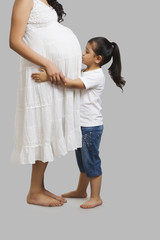 Little girl kissing stomach of pregnant mother