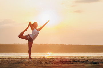 Fototapeta na wymiar Pretty woman doing yoga at sunset outdoors