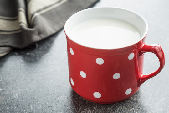 Milk in red mug with white spots.