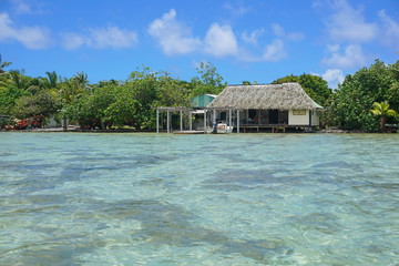 Shallow water of the lagoon with typical home on the shore of an islet, Huahine island, Pacific ocean, French Polynesia