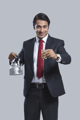 Portrait of smiling businessman offering tea over gray background