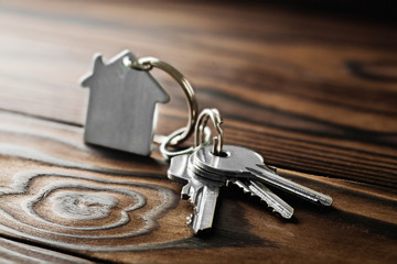 estate concept with symbol of house, key on wooden background