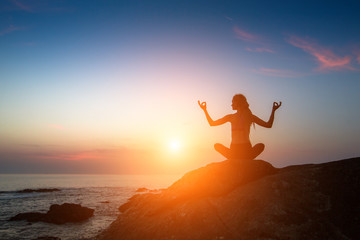 Yoga meditation woman silhouette on the Sea during amazing sunset. Healthy lifestyle.
