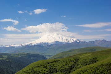Высокая гора Эльбрус, снежные вершины в белых облаках, горы Северного Кавказа