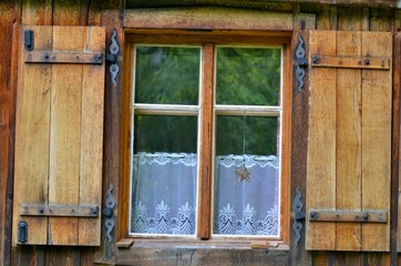 Old wooden window with metallic shutters. Lace curtains below. Vintage window from weekend house, Czech Republic.