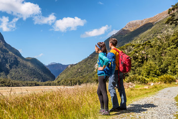 New Zealand hikers backpackers tramping on Routeburn Track, famous trail in the South Island of New Zealand. Couple looking at nature landscape. Fiordland & Mount Aspiring National Park, New Zealand