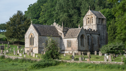 A typical english country scene with old village church set in cemetery surrounded by fields and trees