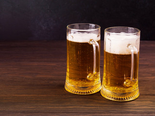 Two glasses of lager served on old wooden planks, copyspace for text