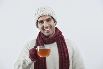 Portrait of happy young man drinking black tea over colored background 