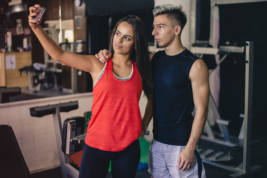 Happy young couple taking selfie at the gym after workout