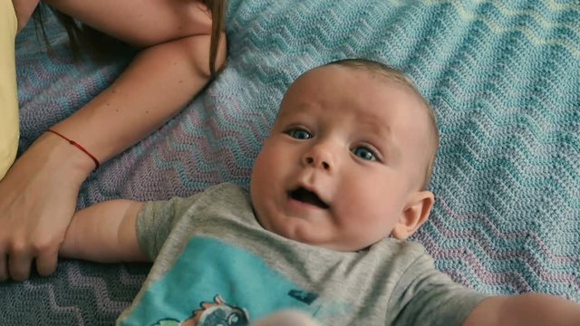 Portrait of adorable blue-eyed baby on the bed plays with toy
