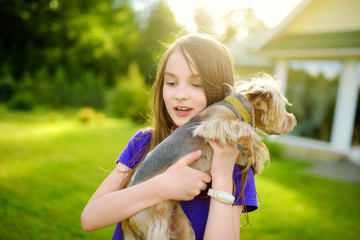 Cute little girl holding her funny yorkshire terrier dog