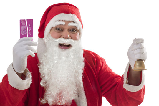 Portrait of cheerful Santa Claus showing gift voucher card with bell in other hand 