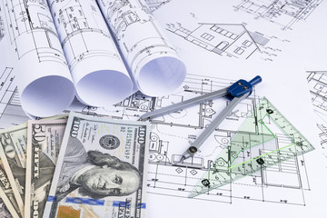A blueprint of an architect with money. Symbolic photo for financing and planning of a new house. Blueprints rolls and a drawing instruments on the worktable