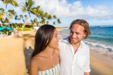 Hawaii travel beach couple laughing together happy on honeymoon vacation. People enjoying hawaiian sunset holidays.