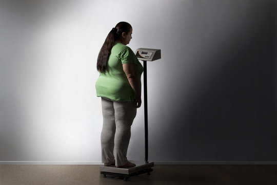 Obese woman checking her weight 
